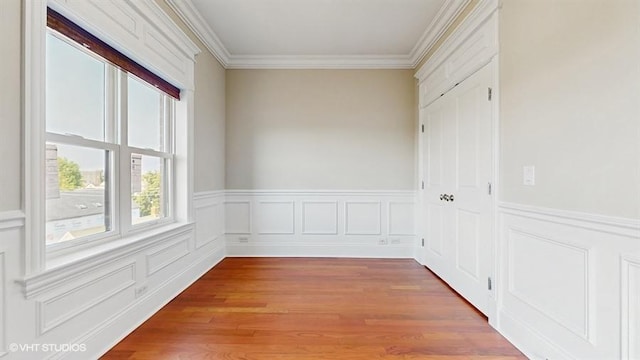 2540 W Diversey Ave Unit 404, Chicago, IL 60647 - unfurnished room featuring crown molding, wainscoting, light wood-style flooring, and a decorative wall