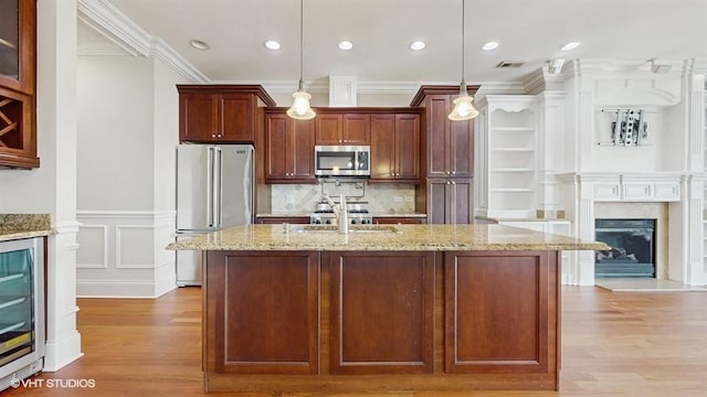 2540 W Diversey Ave Unit 404, Chicago, IL 60647 - kitchen featuring stainless steel appliances, a sink, light wood-style flooring, crown molding, and a premium fireplace