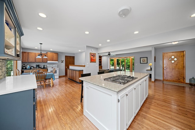 28 Lions Rd, Sandwich, IL 60548 - kitchen with stainless steel gas cooktop, white range with electric cooktop, light wood-type flooring, ceiling fan, and a kitchen island