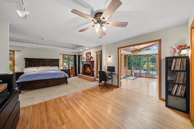 28 Lions Rd, Sandwich, IL 60548 - bedroom with light wood-style flooring, a lit fireplace, a ceiling fan, and a raised ceiling
