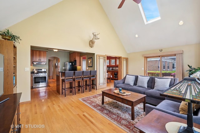 9008 Marmora Ave, Morton Grove, IL 60053 - living area featuring high vaulted ceiling, arched walkways, light wood-style flooring, ceiling fan, and a skylight