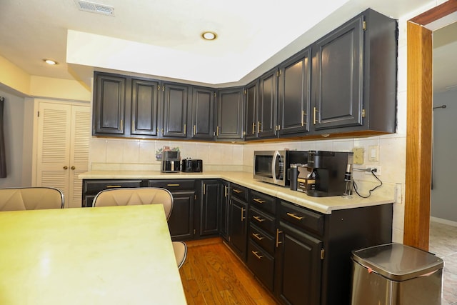 19421 W Hoag Ct, Mundelein, IL 60060 - kitchen featuring stainless steel microwave, light countertops, decorative backsplash, recessed lighting, and wood finished floors
