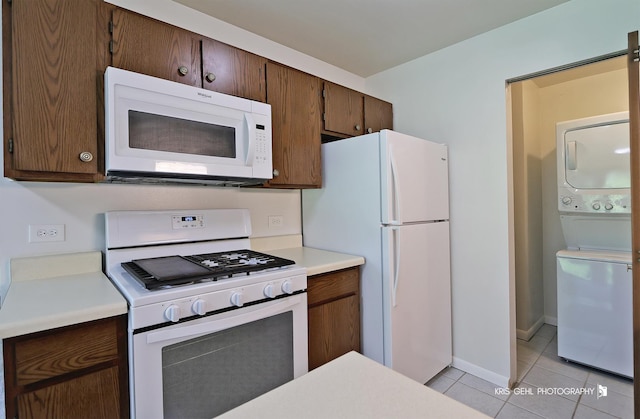 620 Mallard Ct Unit C1, Bartlett, IL 60103 - kitchen featuring white appliances, stacked washer / dryer, light tile patterned flooring, light countertops, and baseboards