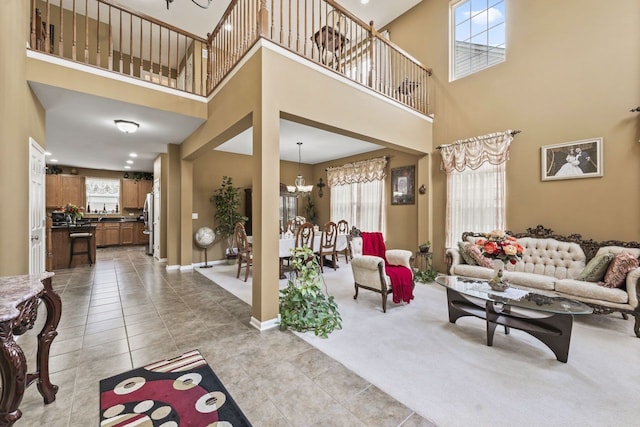 2023 Torino Dr, Elgin, IL 60123 - living area featuring a high ceiling, a chandelier, light tile patterned floors, baseboards, and light carpet