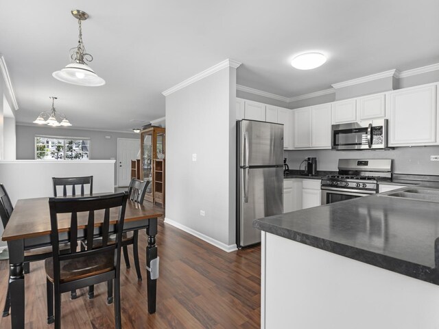 2455 Hillsboro Ln, Montgomery, IL 60538 - kitchen with stainless steel appliances, dark countertops, ornamental molding, dark wood-style floors, and white cabinets