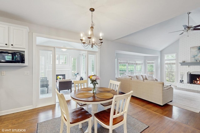 3432 Redwing Dr, Naperville, IL 60564 - dining space featuring a fireplace, wood finished floors, lofted ceiling, a ceiling fan, and a chandelier