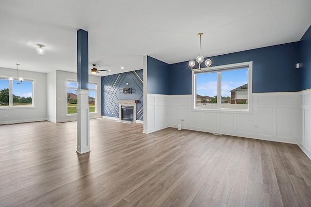 4951 W Ribbon Dr, Monee, IL 60449 - unfurnished living room featuring a chandelier, a glass covered fireplace, a decorative wall, a ceiling fan, and wood finished floors