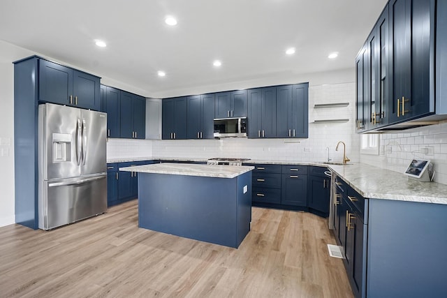 4951 W Ribbon Dr, Monee, IL 60449 - kitchen featuring stainless steel appliances, blue cabinets, light wood-style floors, a kitchen island, and tasteful backsplash