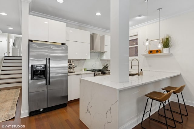 3020 N Sheffield Ave Unit 1N, Chicago, IL 60657 - kitchen featuring appliances with stainless steel finishes, wall chimney range hood, a peninsula, crown molding, and white cabinetry