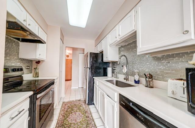 600 Naples Ct Unit 107, Glenview, IL 60025 - kitchen featuring appliances with stainless steel finishes, a sink, under cabinet range hood, white cabinetry, and backsplash