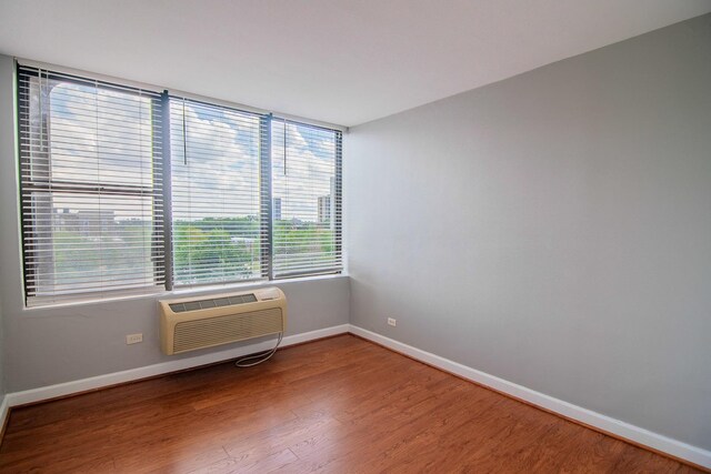 345 E Eastgate Pl Unit 505, Chicago, IL 60616 - spare room featuring wood finished floors, baseboards, and an AC wall unit