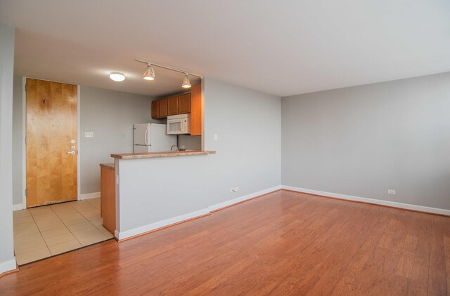 345 E Eastgate Pl Unit 505, Chicago, IL 60616 - kitchen with white appliances, rail lighting, light wood finished floors, light countertops, and a peninsula