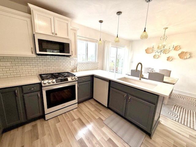 1567 Windward Dr, Pingree Grove, IL 60140 - kitchen featuring appliances with stainless steel finishes, a sink, tasteful backsplash, light countertops, and a chandelier