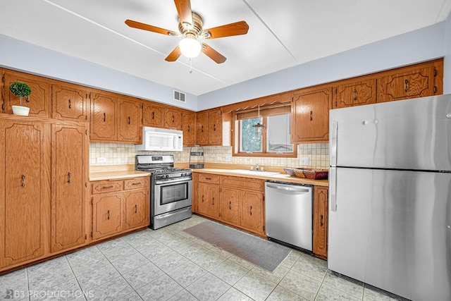 8124 168th Pl Unit 1E, Tinley Park, IL 60477 - kitchen with appliances with stainless steel finishes, brown cabinetry, backsplash, and light countertops