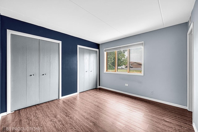 8124 168th Pl Unit 1E, Tinley Park, IL 60477 - unfurnished bedroom with multiple closets, wood finished floors, and baseboards