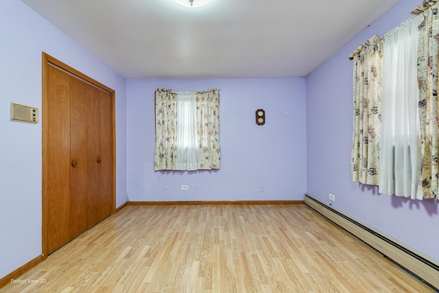 1903 Marshall Pkwy, Waukegan, IL 60085 - unfurnished bedroom featuring a baseboard radiator, wood finished floors, a closet, and baseboards