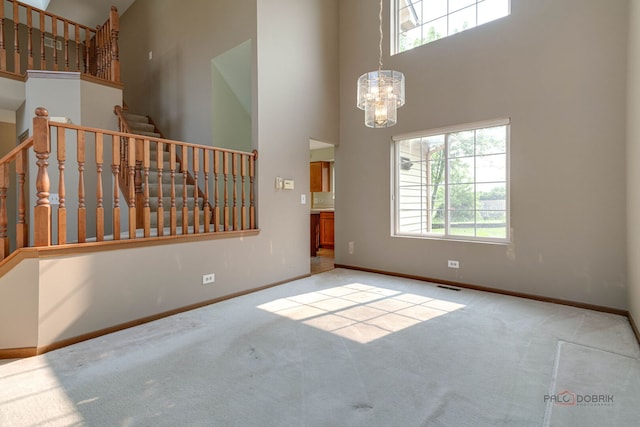 1927 Oaktree Trl, Lake Villa, IL 60046 - carpeted empty room featuring a high ceiling, baseboards, a chandelier, and stairway