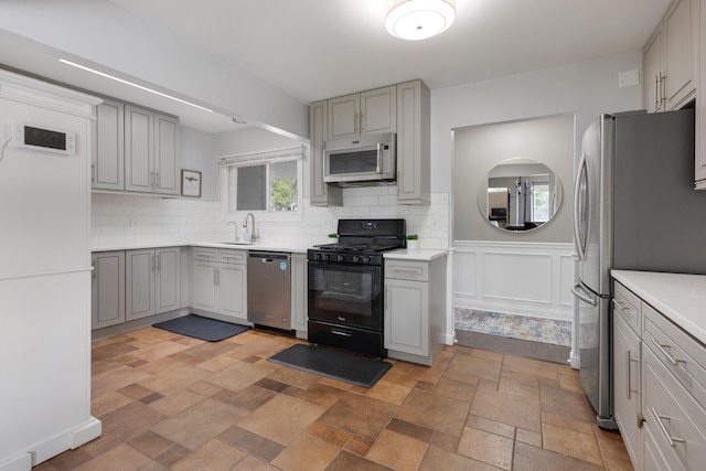 1850 Pierce Rd, Hoffman Estates, IL 60169 - kitchen with appliances with stainless steel finishes, a sink, gray cabinetry, decorative backsplash, and a wainscoted wall