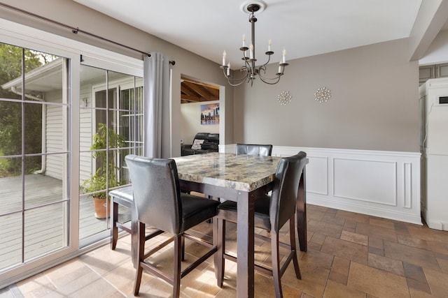 1850 Pierce Rd, Hoffman Estates, IL 60169 - dining space featuring a chandelier, stone tile floors, and a wainscoted wall