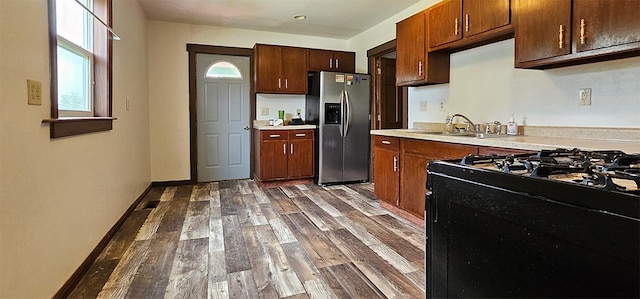 1 S Stanton St, Shannon, IL 61078 - kitchen featuring stainless steel refrigerator with ice dispenser, black gas stove, dark wood-style floors, light countertops, and a sink