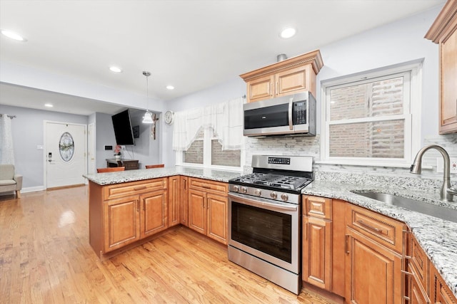 5642 W Dakin St, Chicago, IL 60634 - kitchen with stainless steel appliances, a sink, a peninsula, light wood-style flooring, and backsplash