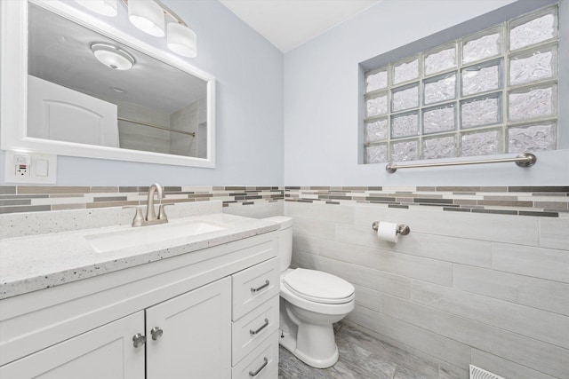 5642 W Dakin St, Chicago, IL 60634 - full bathroom with tile walls, toilet, vanity, a shower, and a wainscoted wall