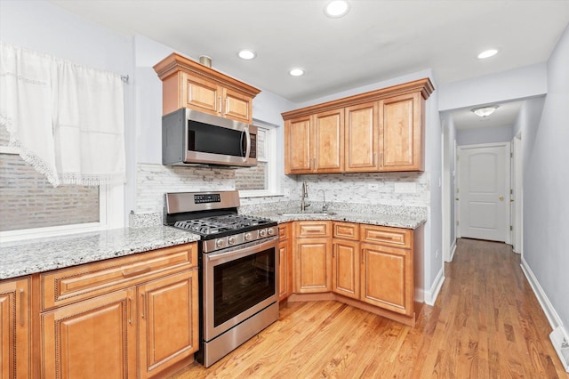 5642 W Dakin St, Chicago, IL 60634 - kitchen featuring stainless steel appliances, a sink, decorative backsplash, light wood-type flooring, and light stone countertops