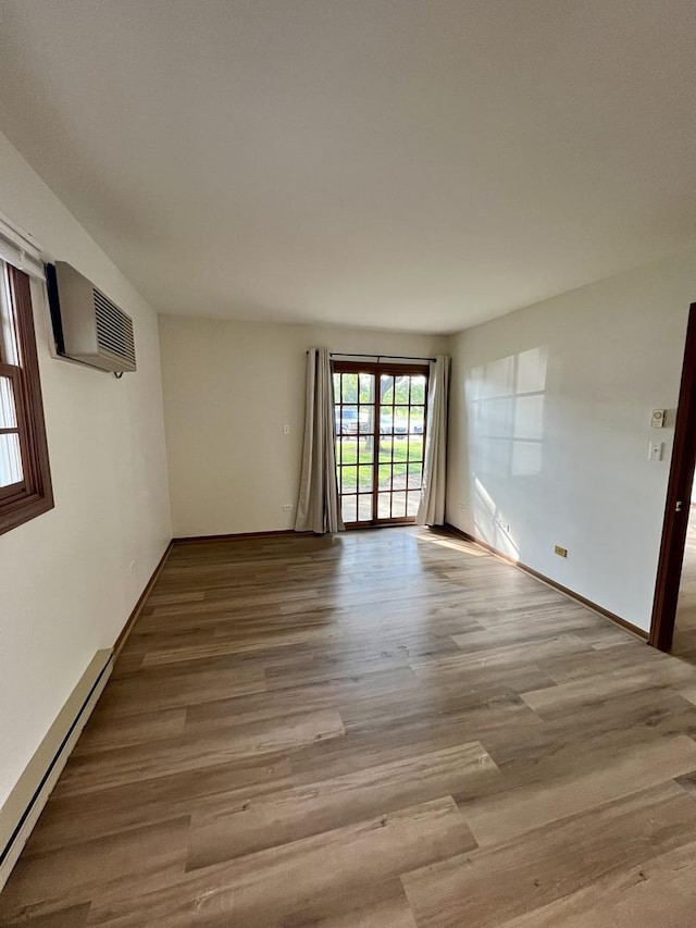 4400 W Shamrock Ln Unit 1B, Mchenry, IL 60050 - spare room with baseboard heating, an AC wall unit, wood finished floors, and baseboards