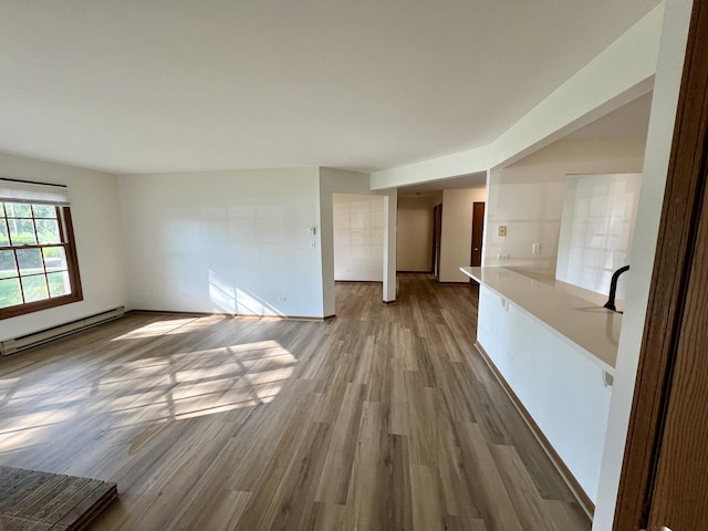 4400 W Shamrock Ln Unit 1B, Mchenry, IL 60050 - unfurnished living room featuring a baseboard heating unit, wood finished floors, and baseboards