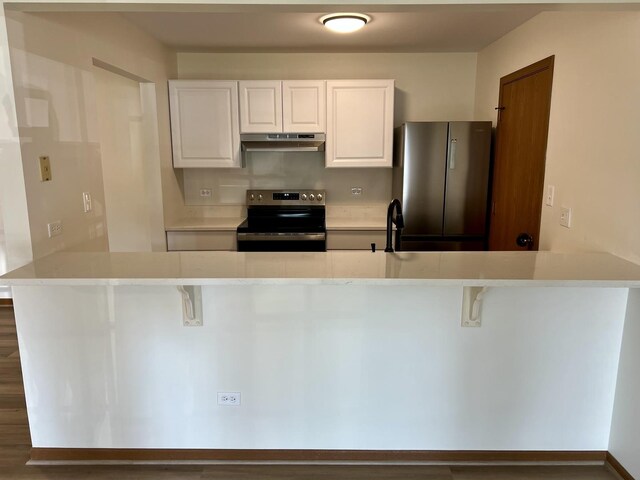 4400 W Shamrock Ln Unit 1B, Mchenry, IL 60050 - kitchen with electric stove, freestanding refrigerator, under cabinet range hood, a peninsula, and white cabinetry