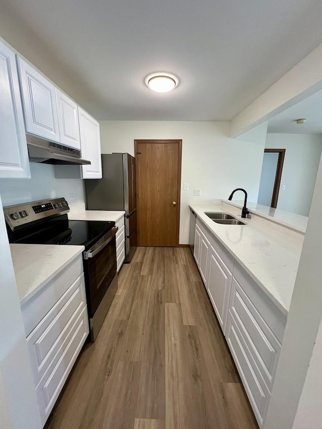 4400 W Shamrock Ln Unit 1B, Mchenry, IL 60050 - kitchen featuring under cabinet range hood, stainless steel appliances, a sink, wood finished floors, and white cabinets