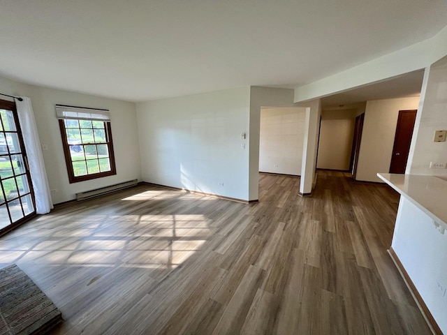 4400 W Shamrock Ln Unit 1B, Mchenry, IL 60050 - empty room featuring a baseboard radiator, wood finished floors, and baseboards