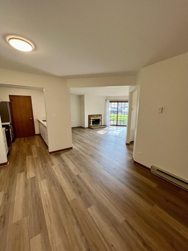 4400 W Shamrock Ln Unit 1B, Mchenry, IL 60050 - unfurnished living room featuring wood finished floors, a brick fireplace, and baseboards
