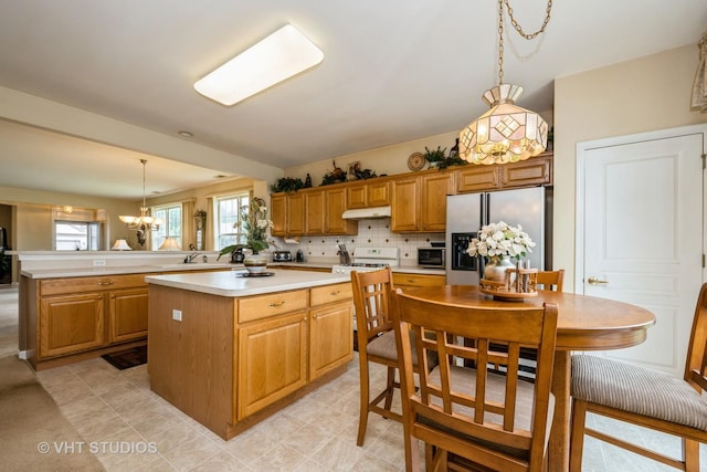 12140 Hideaway Dr, Huntley, IL 60142 - kitchen featuring stainless steel fridge, a peninsula, light countertops, a chandelier, and under cabinet range hood