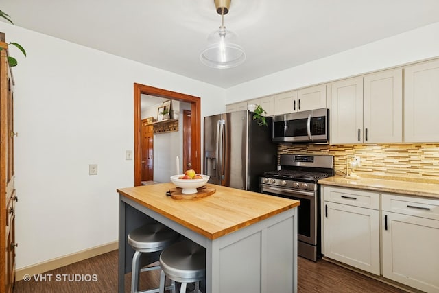 207 S Van Buren St, East Dundee, IL 60118 - kitchen featuring appliances with stainless steel finishes, butcher block countertops, decorative backsplash, a breakfast bar, and dark wood-style flooring