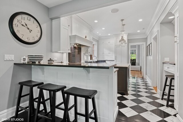 739 Jackson Ave, River Forest, IL 60305 - kitchen with white cabinetry, a kitchen bar, a peninsula, ornamental molding, and decorative light fixtures