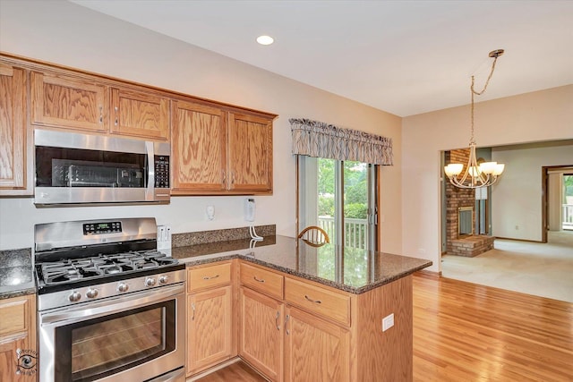 82 Whisper Creek Dr, New Lenox, IL 60451 - kitchen featuring appliances with stainless steel finishes, a chandelier, a peninsula, dark stone counters, and pendant lighting