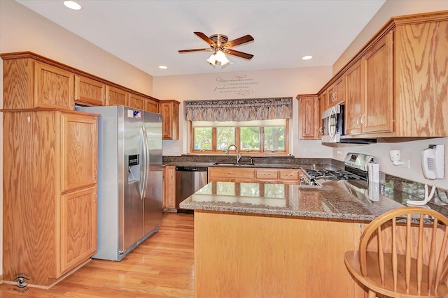 82 Whisper Creek Dr, New Lenox, IL 60451 - kitchen with appliances with stainless steel finishes, a peninsula, light wood finished floors, a ceiling fan, and dark stone counters