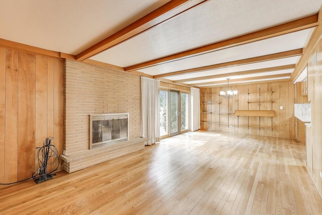 1904 Birch Rd, Northbrook, IL 60062 - unfurnished living room featuring a chandelier, beamed ceiling, wood walls, hardwood / wood-style flooring, and a brick fireplace