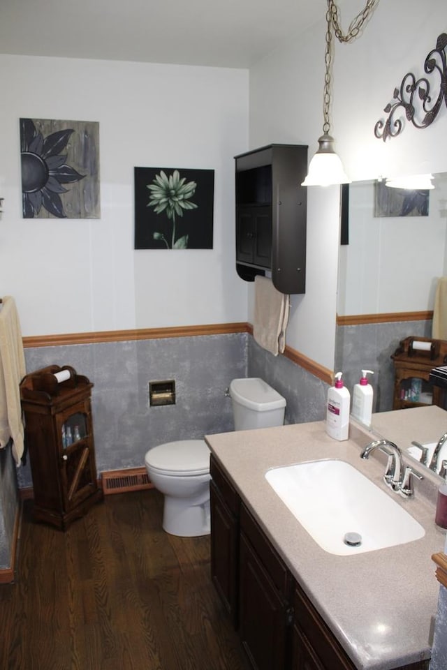 907 N Eddy St, Sandwich, IL 60548 - bathroom featuring wood finished floors, toilet, vanity, wainscoting, and tile walls