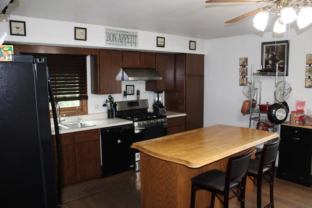 907 N Eddy St, Sandwich, IL 60548 - kitchen with black appliances, under cabinet range hood, dark wood-style flooring, light countertops, and a ceiling fan