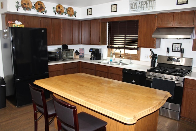907 N Eddy St, Sandwich, IL 60548 - kitchen with black appliances, under cabinet range hood, a sink, dark wood finished floors, and a breakfast bar