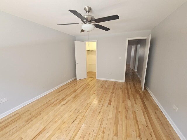 5349 N Delphia Ave Unit 150, Chicago, IL 60656 - unfurnished bedroom with light wood-style floors, a walk in closet, baseboards, a closet, and a ceiling fan
