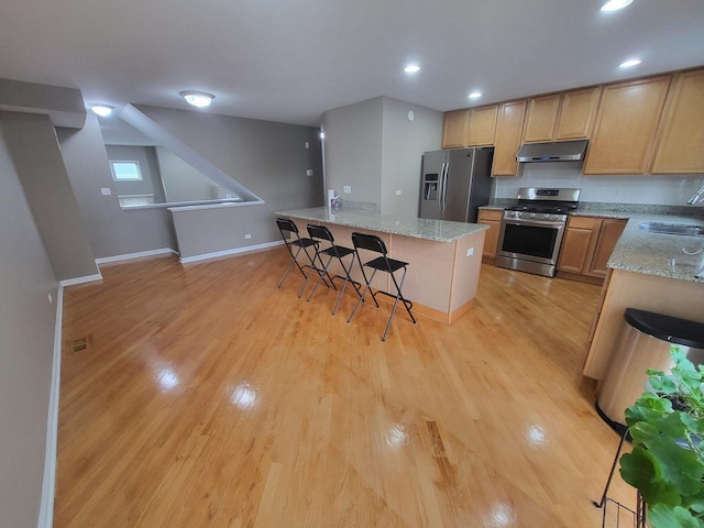 3041 W Pope John Paul Ii Dr, Chicago, IL 60638 - kitchen featuring stainless steel appliances, under cabinet range hood, a kitchen breakfast bar, light wood-type flooring, and a sink