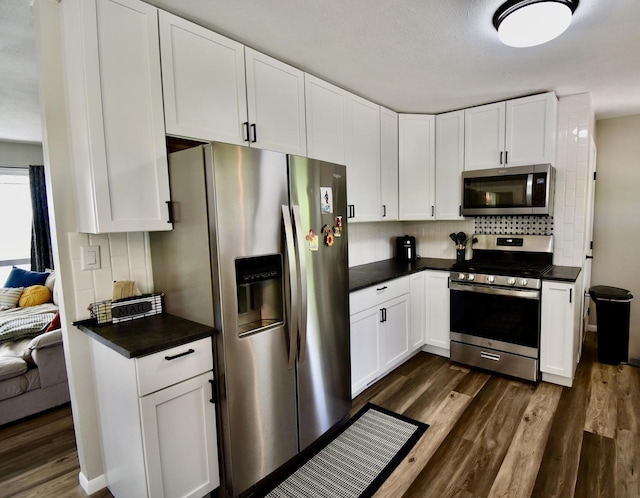 401 W Boundary St, Stanford, IL 61774 - kitchen with stainless steel appliances, dark countertops, tasteful backsplash, dark wood-style floors, and white cabinetry