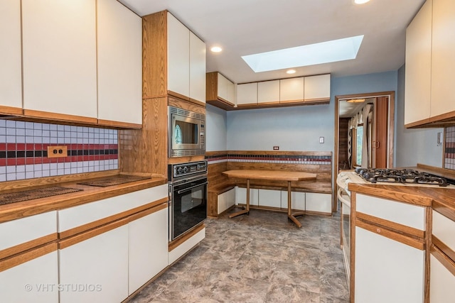 945 S Wolf Rd, Des Plaines, IL 60016 - kitchen with black appliances, a skylight, wooden counters, white cabinetry, and a wainscoted wall