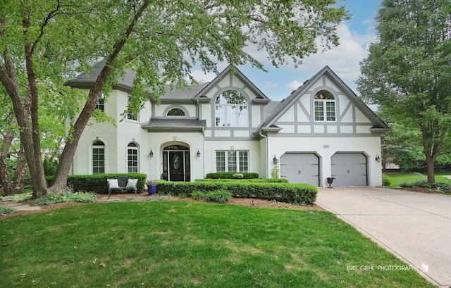 2515 Thurston Ct, Aurora, IL 60502 - tudor-style house featuring concrete driveway, a front yard, a garage, stucco siding, and a shingled roof