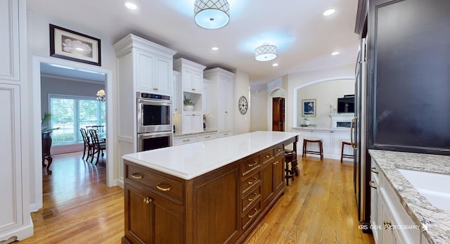 2515 Thurston Ct, Aurora, IL 60502 - kitchen featuring stainless steel double oven, arched walkways, white cabinets, light wood-style flooring, and recessed lighting