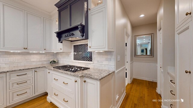 2515 Thurston Ct, Aurora, IL 60502 - kitchen featuring light wood-style flooring, backsplash, white cabinetry, light stone countertops, and a wainscoted wall