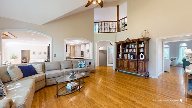 2515 Thurston Ct, Aurora, IL 60502 - living room featuring arched walkways, a towering ceiling, light wood-style flooring, and a ceiling fan